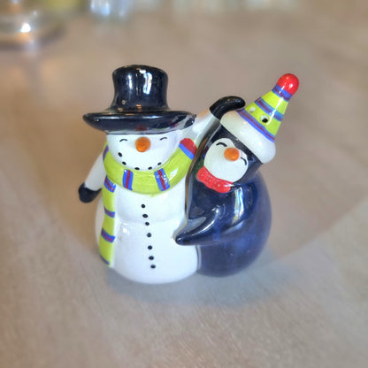 Ceramic salt and pepper shakers shaped as a hugging snowman and penguin.