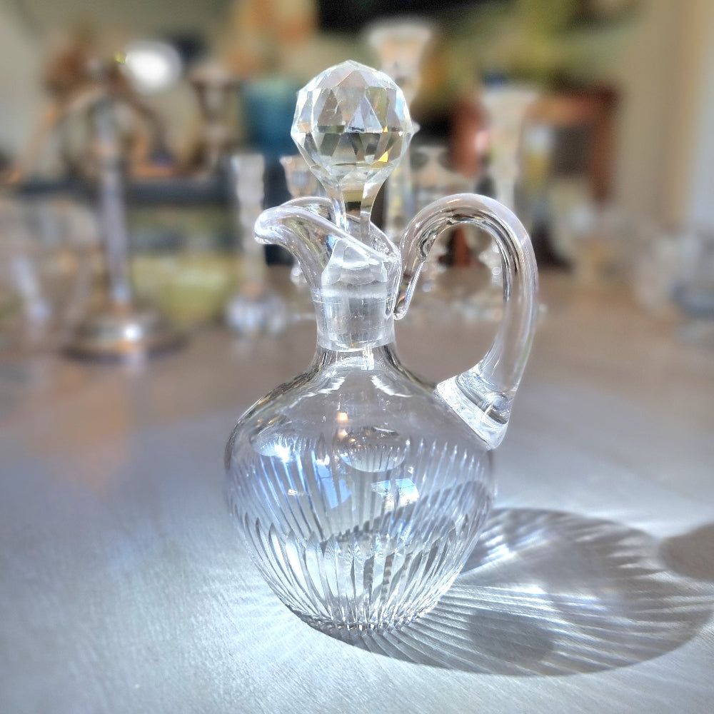 Cut crystal cruet with faceted stopper and ribbed round body.