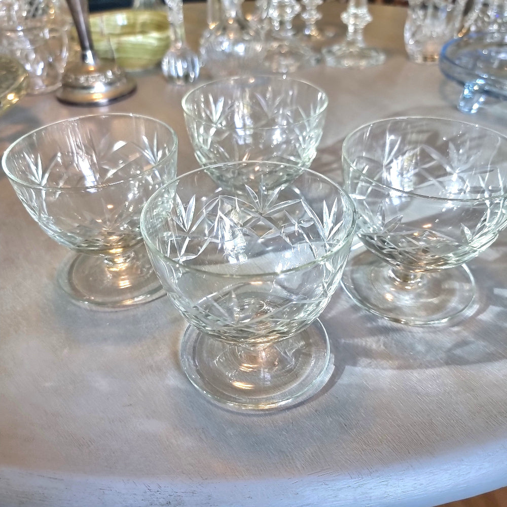 Set of four cut glass dessert bowls with footed bases and etched geometric patterns.