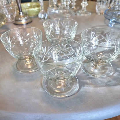 Set of four cut glass dessert bowls with footed bases and etched geometric patterns.