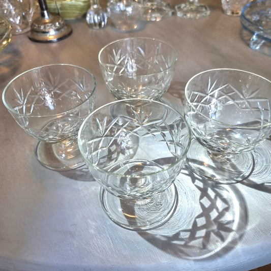 Set of four cut glass dessert bowls with footed bases and etched geometric patterns.