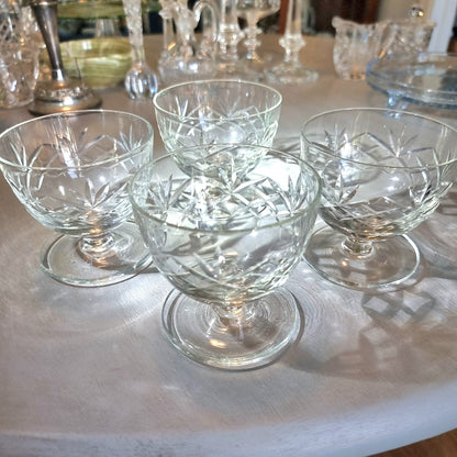 Set of four cut glass dessert bowls with footed bases and etched geometric patterns.