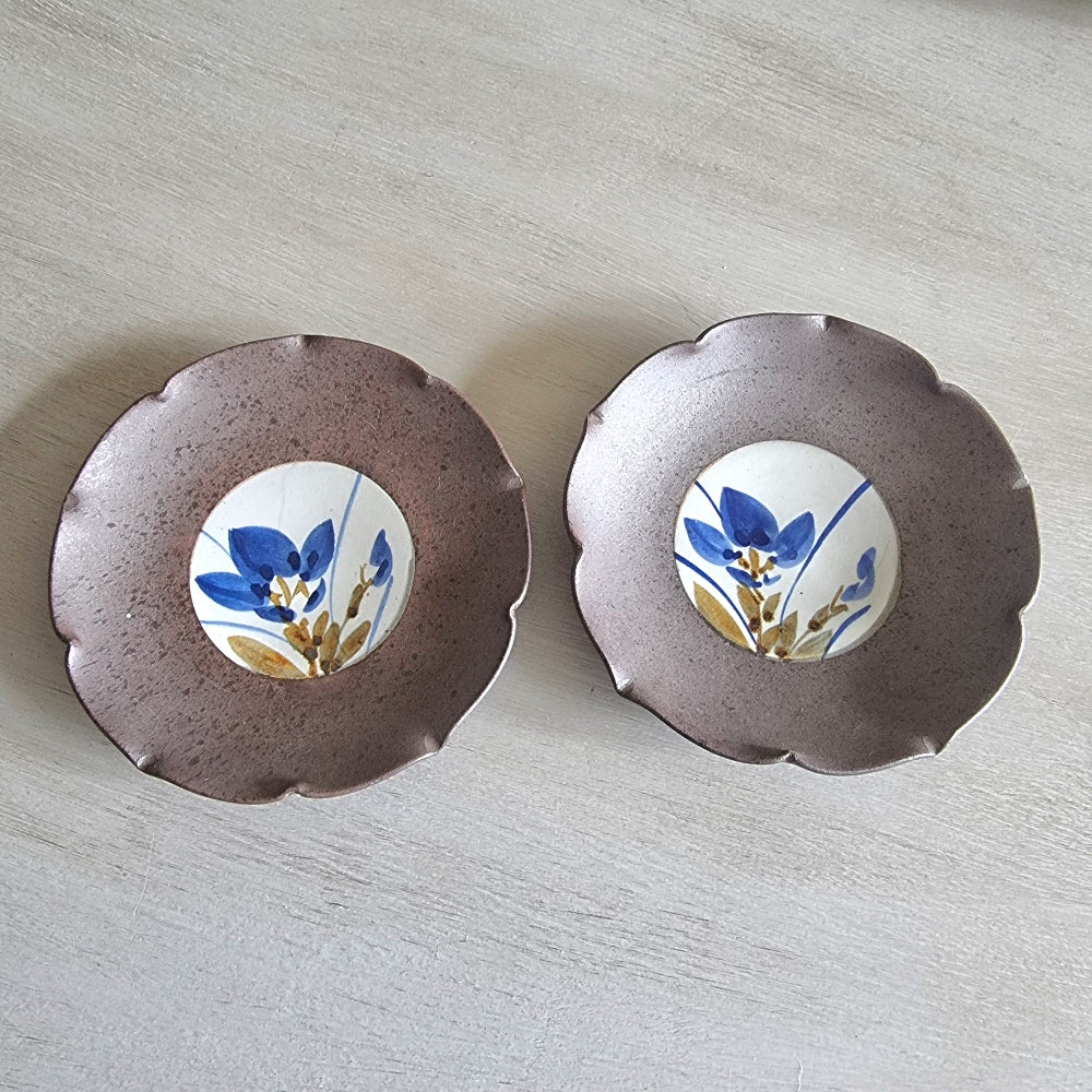 Pair of ceramic dishes with blue floral centres and speckled mauve scalloped rims.