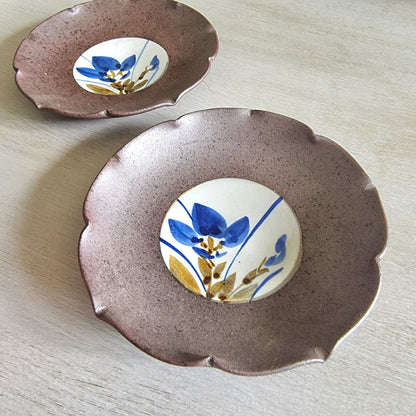 Pair of ceramic dishes with blue floral centres and speckled mauve scalloped rims.