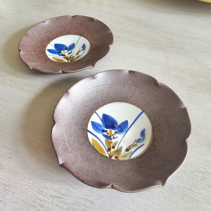 Pair of ceramic dishes with blue floral centres and speckled mauve scalloped rims.