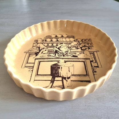 Vintage fluted plate with black pottery workshop illustration on warm yellow glaze.