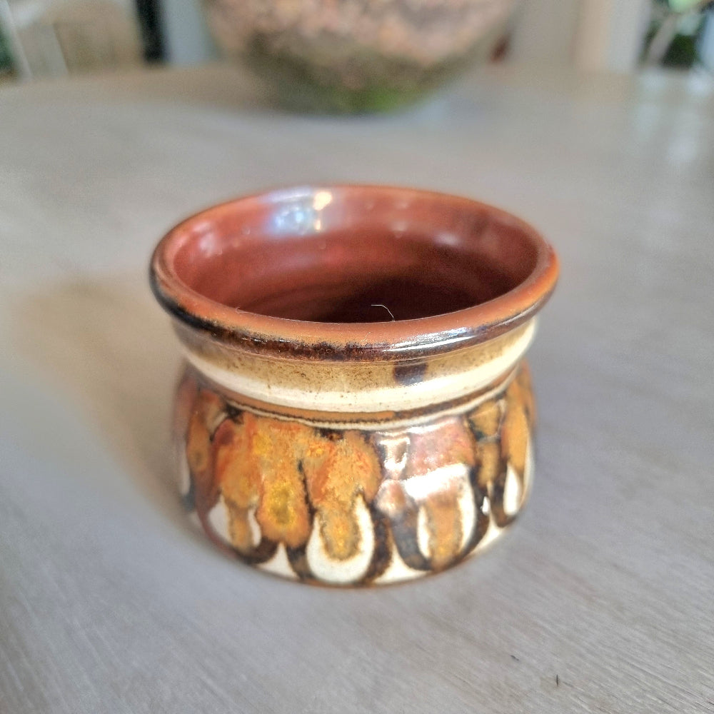 Vintage studio pottery planter with brown, caramel and cream glaze and textured drip pattern on a tabletop.