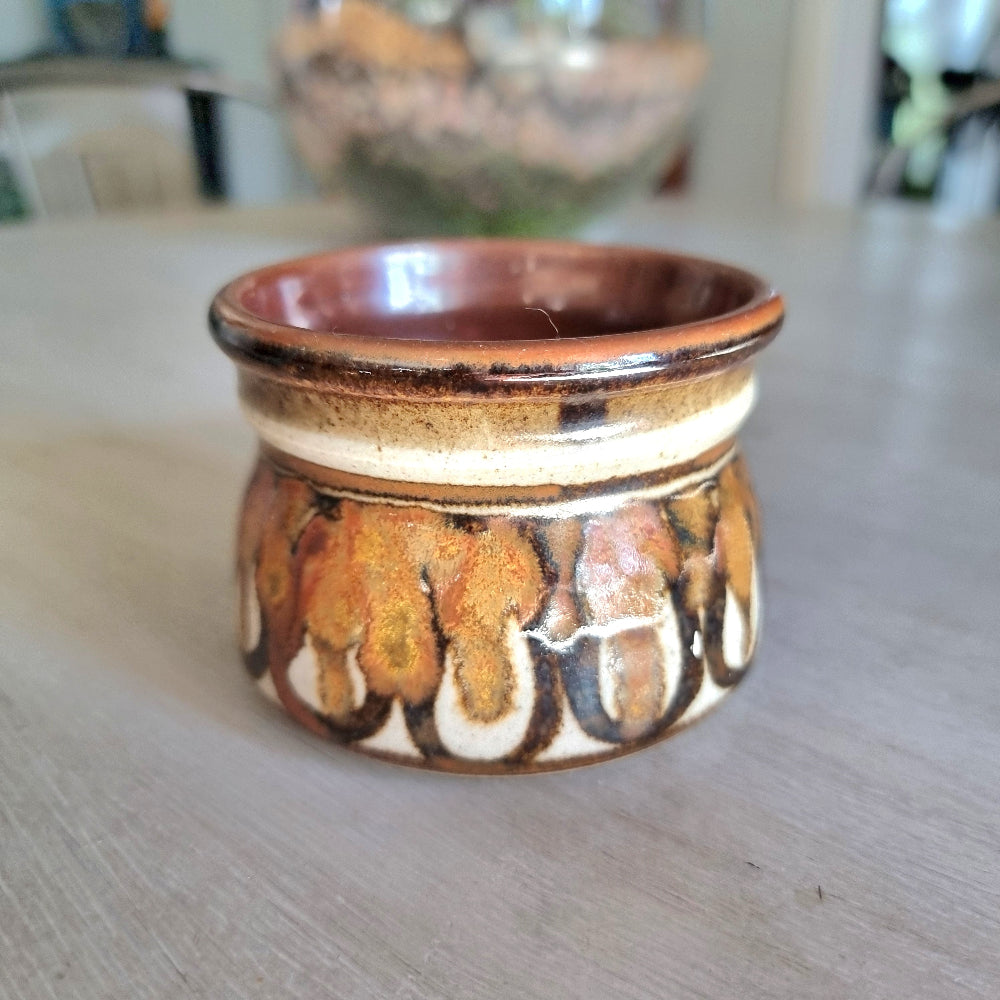 Vintage studio pottery planter with brown, caramel and cream glaze and textured drip pattern on a tabletop.