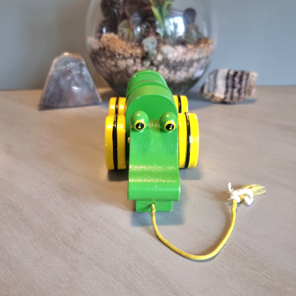 Vintage green wooden pull-along crocodile toy with yellow wheels.