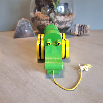 Vintage green wooden pull-along crocodile toy with yellow wheels.