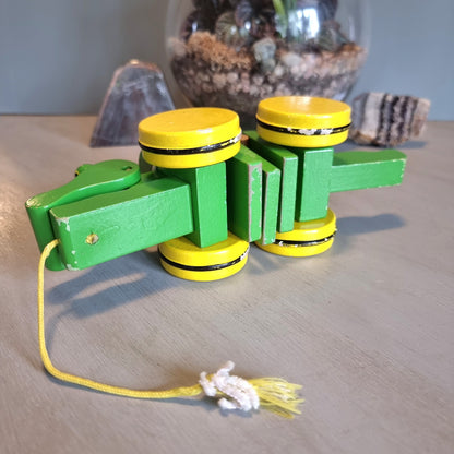 Vintage green wooden pull-along crocodile toy with yellow wheels.
