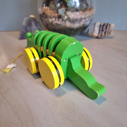 Vintage green wooden pull-along crocodile toy with yellow wheels.