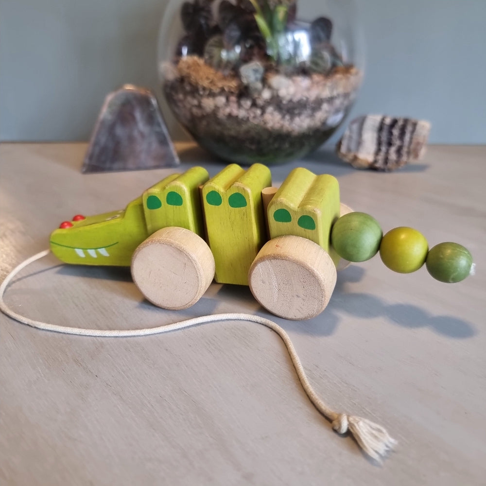 Vintage wooden pull-along crocodile toy in soft green with natural timber wheels