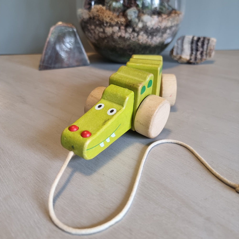 Vintage wooden pull-along crocodile toy in soft green with natural timber wheels