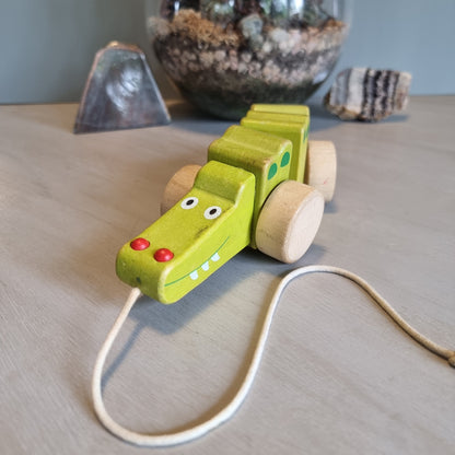 Vintage wooden pull-along crocodile toy in soft green with natural timber wheels