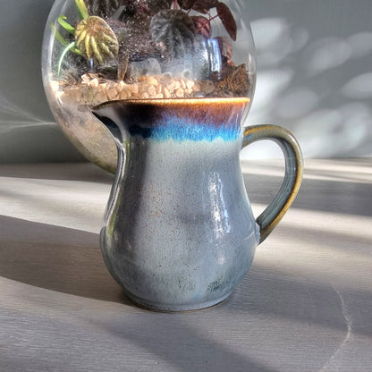 Vintage Clay Craft cream jug with blue reactive glaze and stamped base, styled on a tabletop.