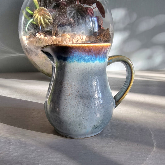 Vintage Clay Craft cream jug with blue reactive glaze and stamped base, styled on a tabletop.