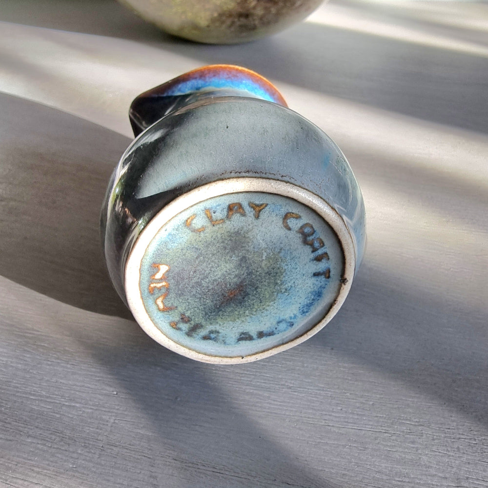 Vintage Clay Craft cream jug with blue reactive glaze and stamped base, styled on a tabletop.