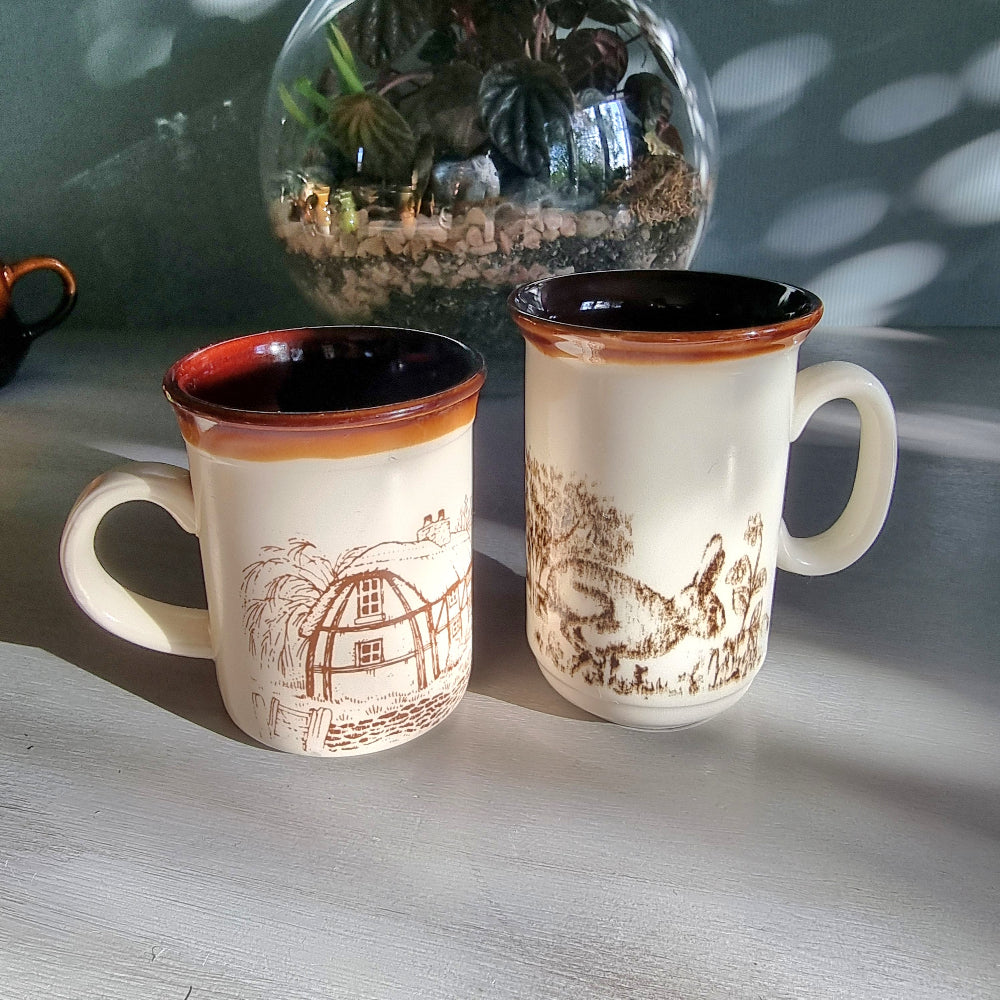 Two vintage English mugs by Bilton and Churchill with rabbit and cottage countryside illustrations on a tabletop.
