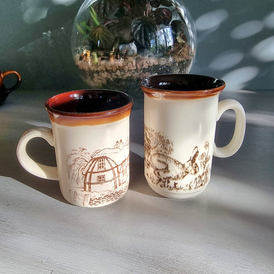 Two vintage English mugs by Bilton and Churchill with rabbit and cottage countryside illustrations on a tabletop.
