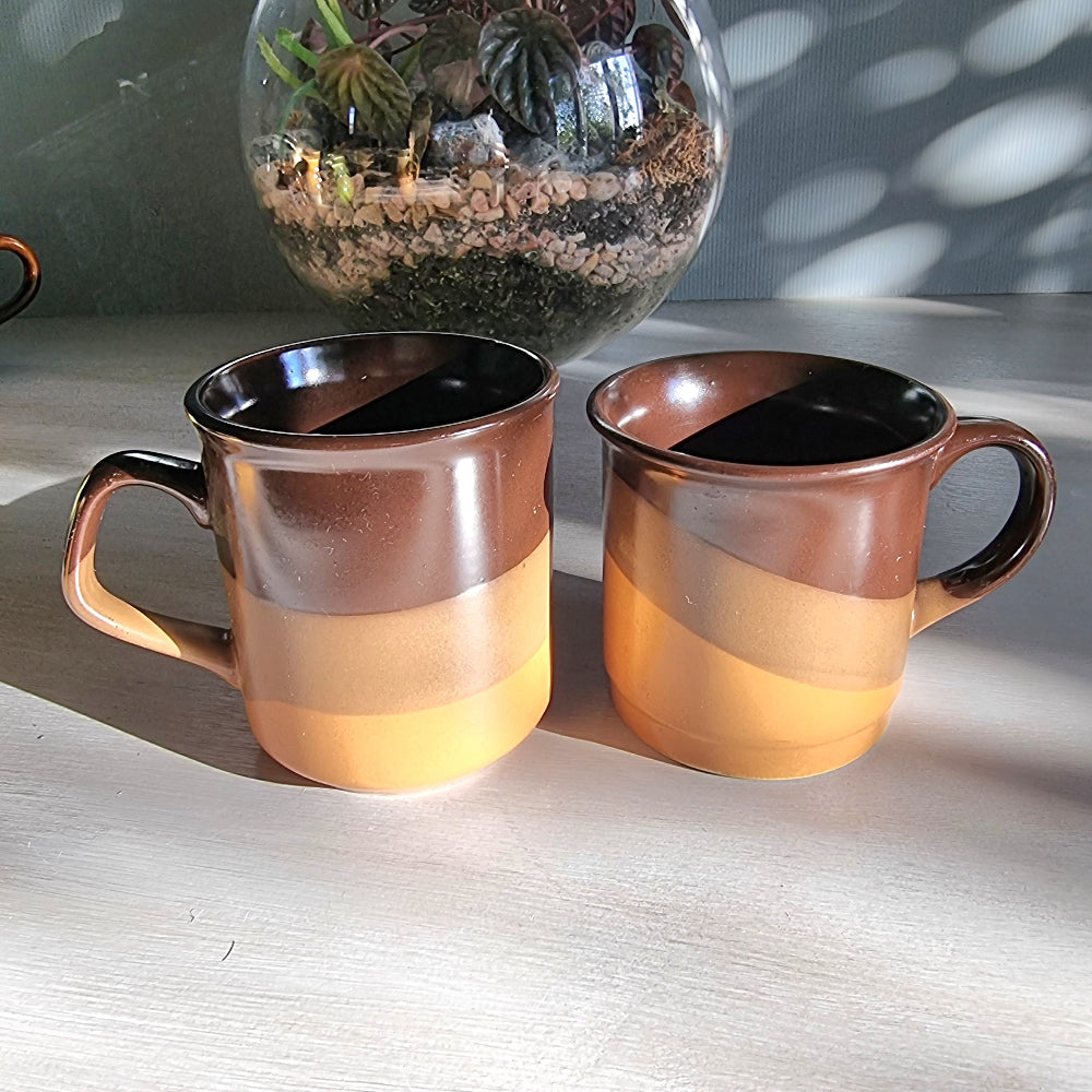 Matching vintage stoneware mugs with banded brown glaze in warm earthy tones