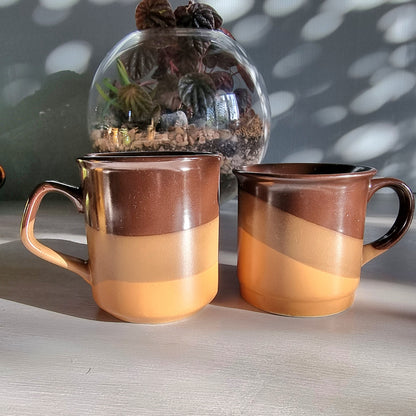 Matching vintage stoneware mugs with banded brown glaze in warm earthy tones