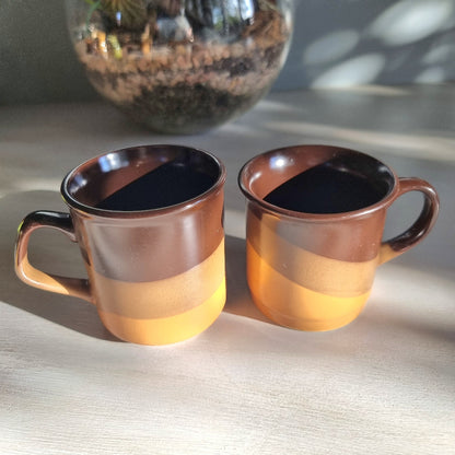 Matching vintage stoneware mugs with banded brown glaze in warm earthy tones