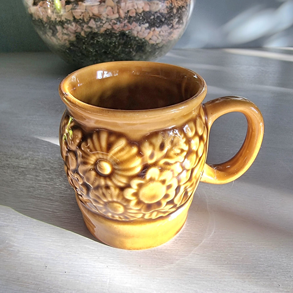 Vintage Crown Lynn floral relief mug in honey-brown glaze with raised flower design, New Zealand pottery.