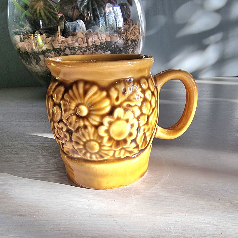 Vintage Crown Lynn floral relief mug in honey-brown glaze with raised flower design, New Zealand pottery.