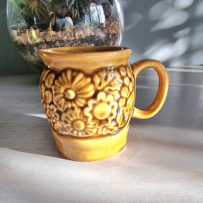 Vintage Crown Lynn floral relief mug in honey-brown glaze with raised flower design, New Zealand pottery.