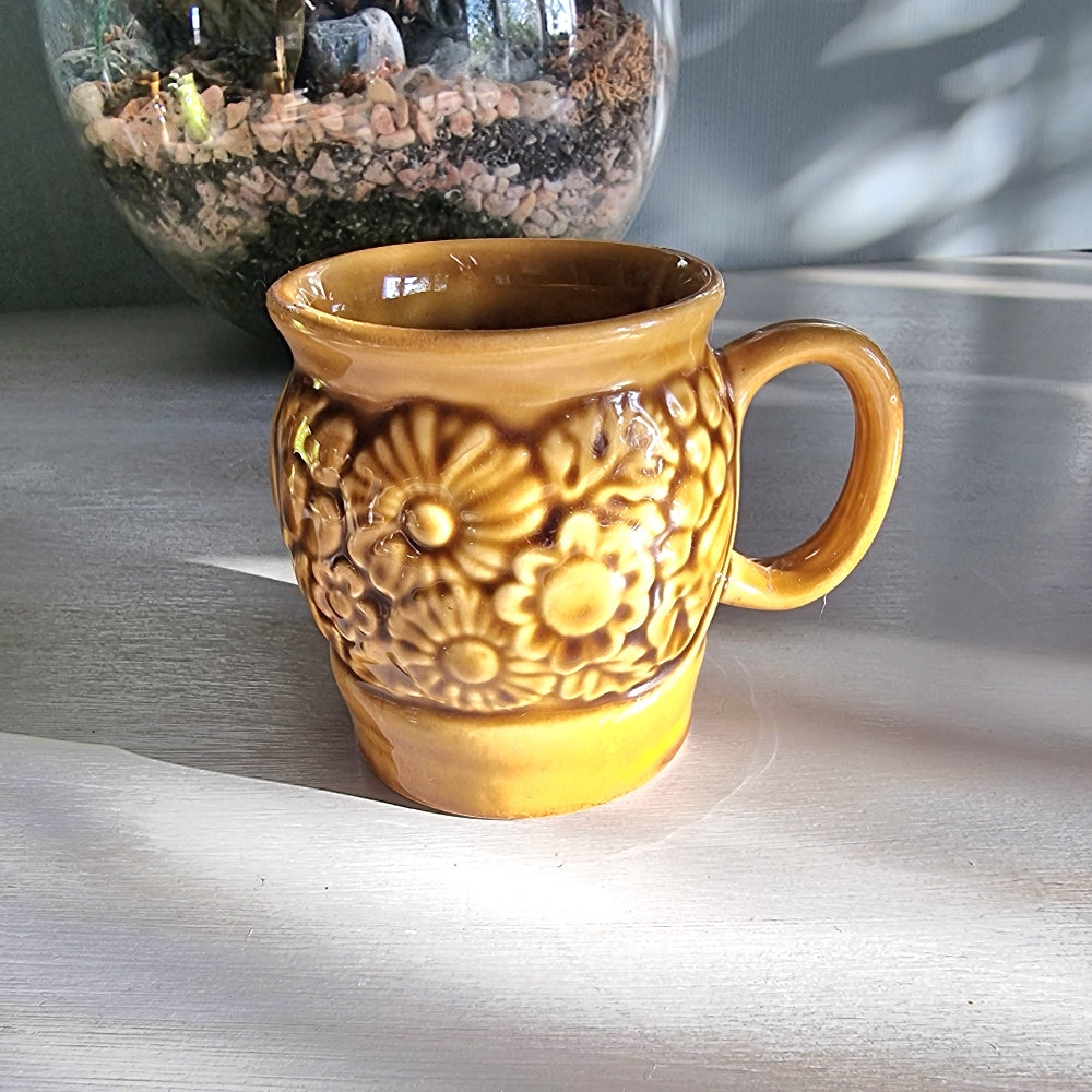 Vintage Crown Lynn floral relief mug in honey-brown glaze with raised flower design, New Zealand pottery.