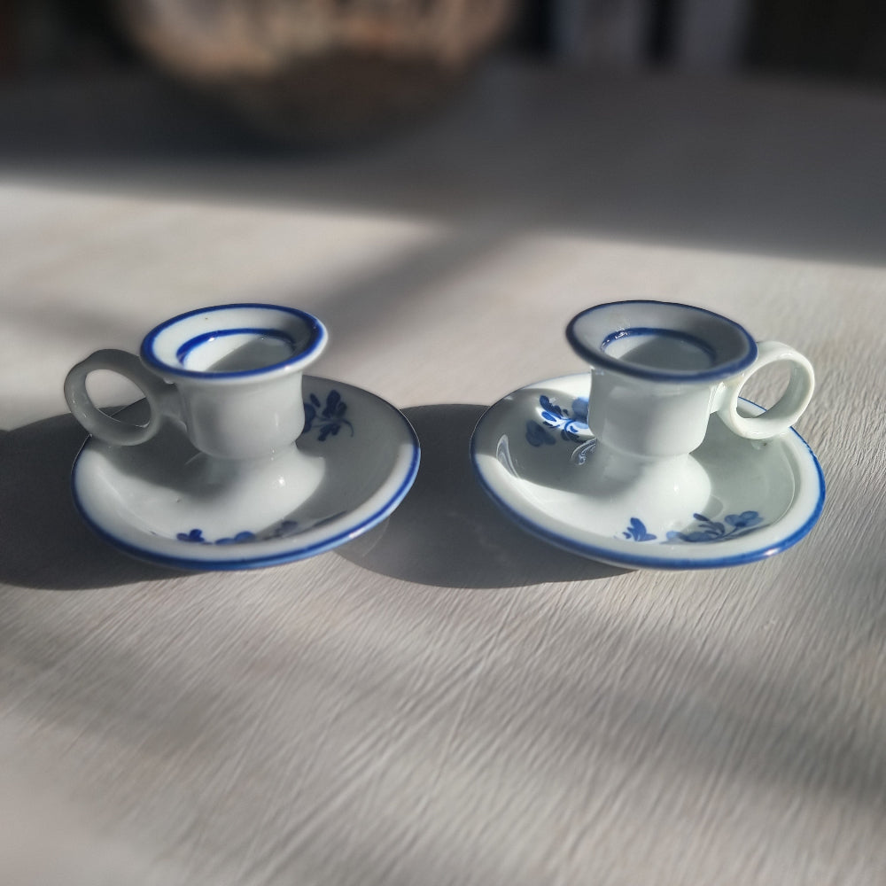 Pair of small blue and white ceramic candle holders with floral design and handles.