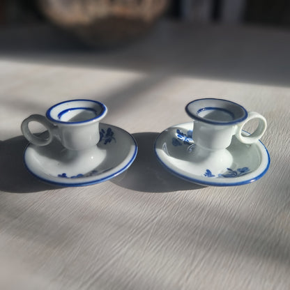 Pair of small blue and white ceramic candle holders with floral design and handles.