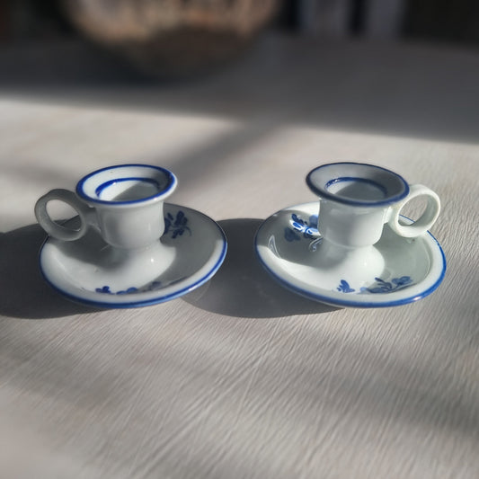Pair of small blue and white ceramic candle holders with floral design and handles.