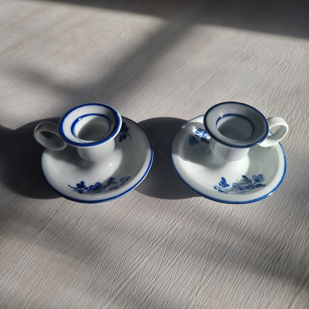 Pair of small blue and white ceramic candle holders with floral design and handles.