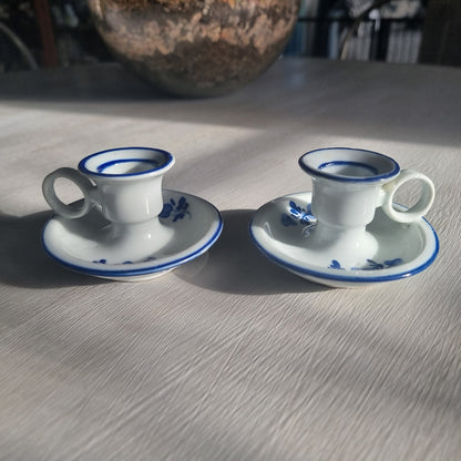 Pair of small blue and white ceramic candle holders with floral design and handles.