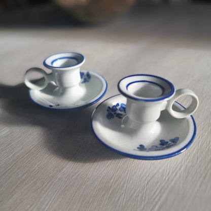 Pair of small blue and white ceramic candle holders with floral design and handles.