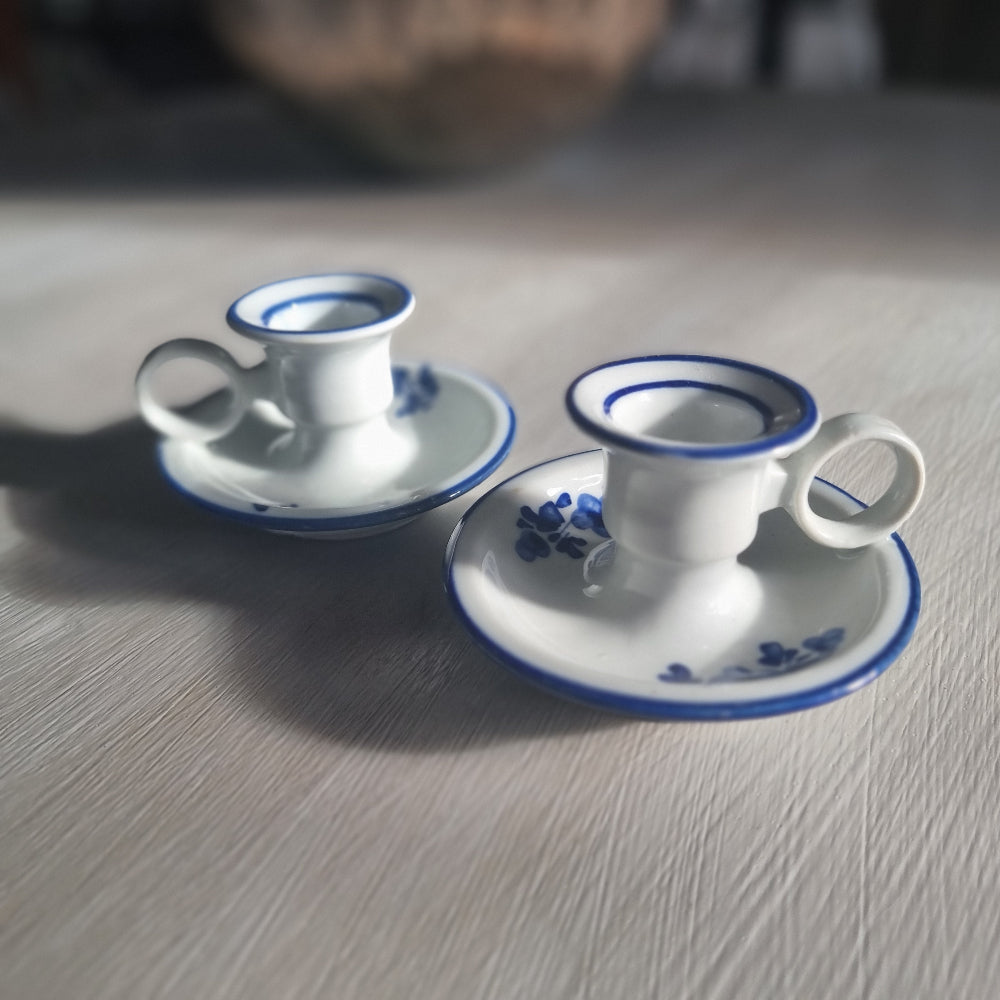 Pair of small blue and white ceramic candle holders with floral design and handles.