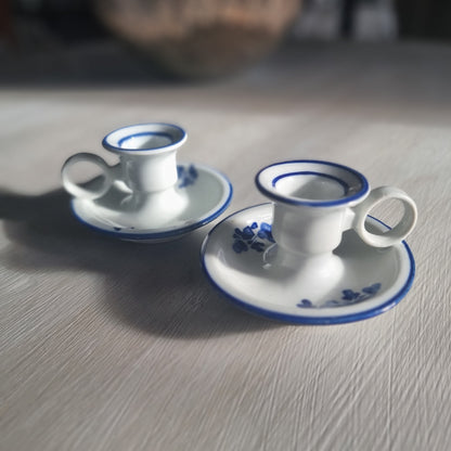Pair of small blue and white ceramic candle holders with floral design and handles.