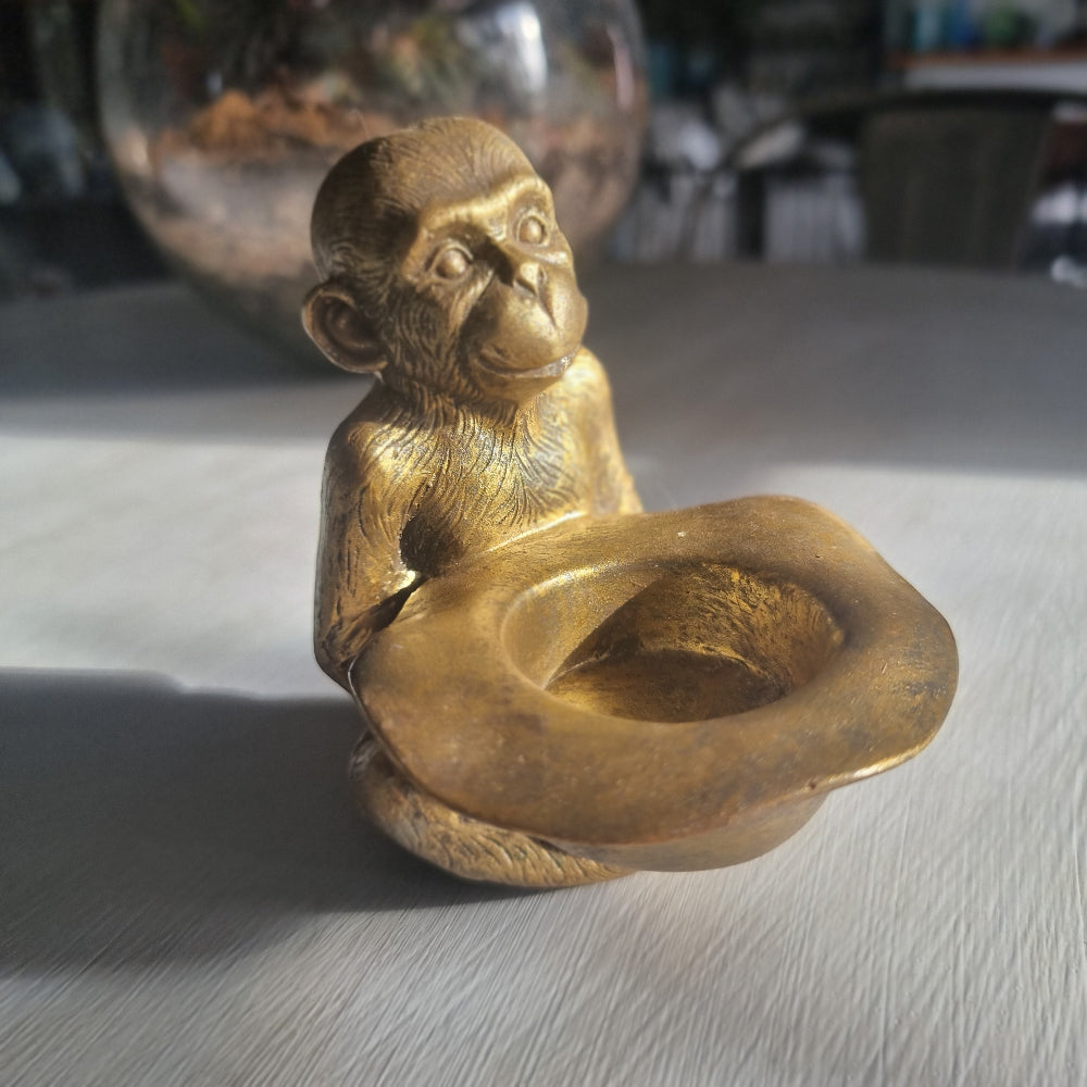 Small gold monkey tealight holder with antique brass-style finish holding candle dish.