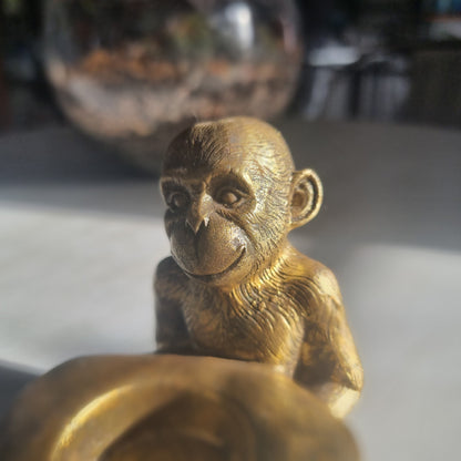 Small gold monkey tealight holder with antique brass-style finish holding candle dish.