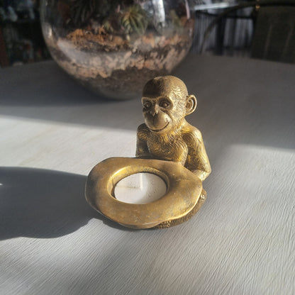 Small gold monkey tealight holder with antique brass-style finish holding candle dish.