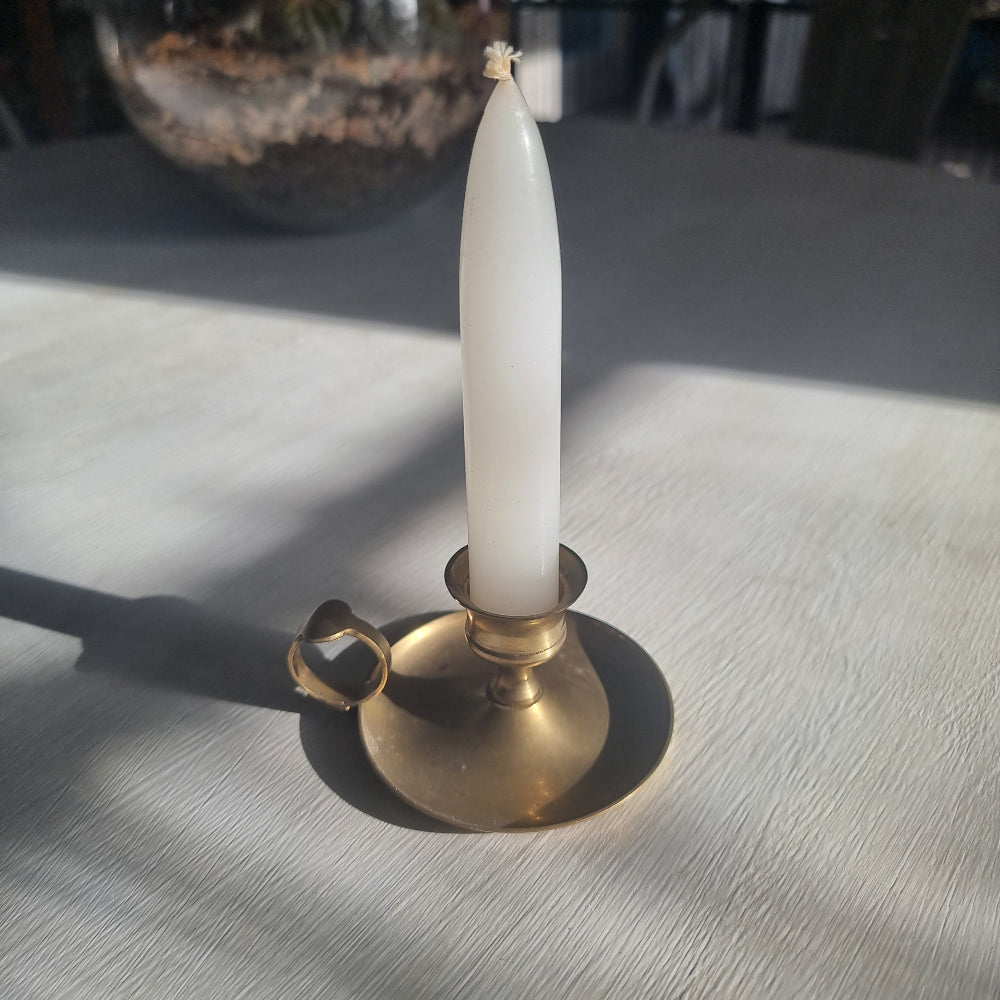 Brass chamber candlestick with round drip tray and finger handle.