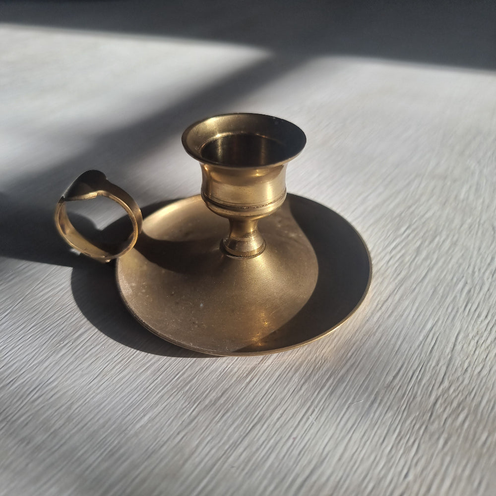 Brass chamber candlestick with round drip tray and finger handle.
