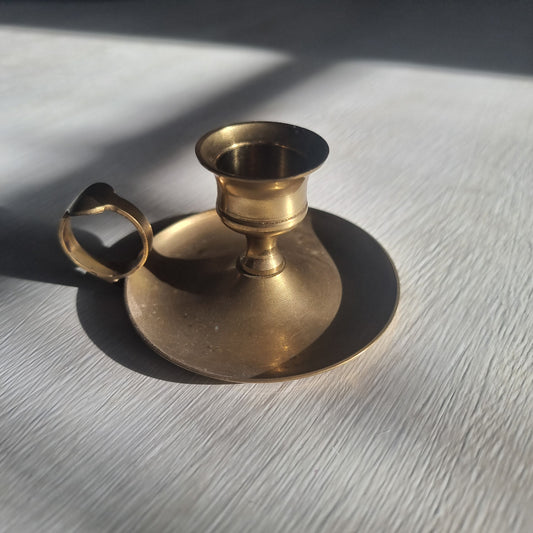 Brass chamber candlestick with round drip tray and finger handle.
