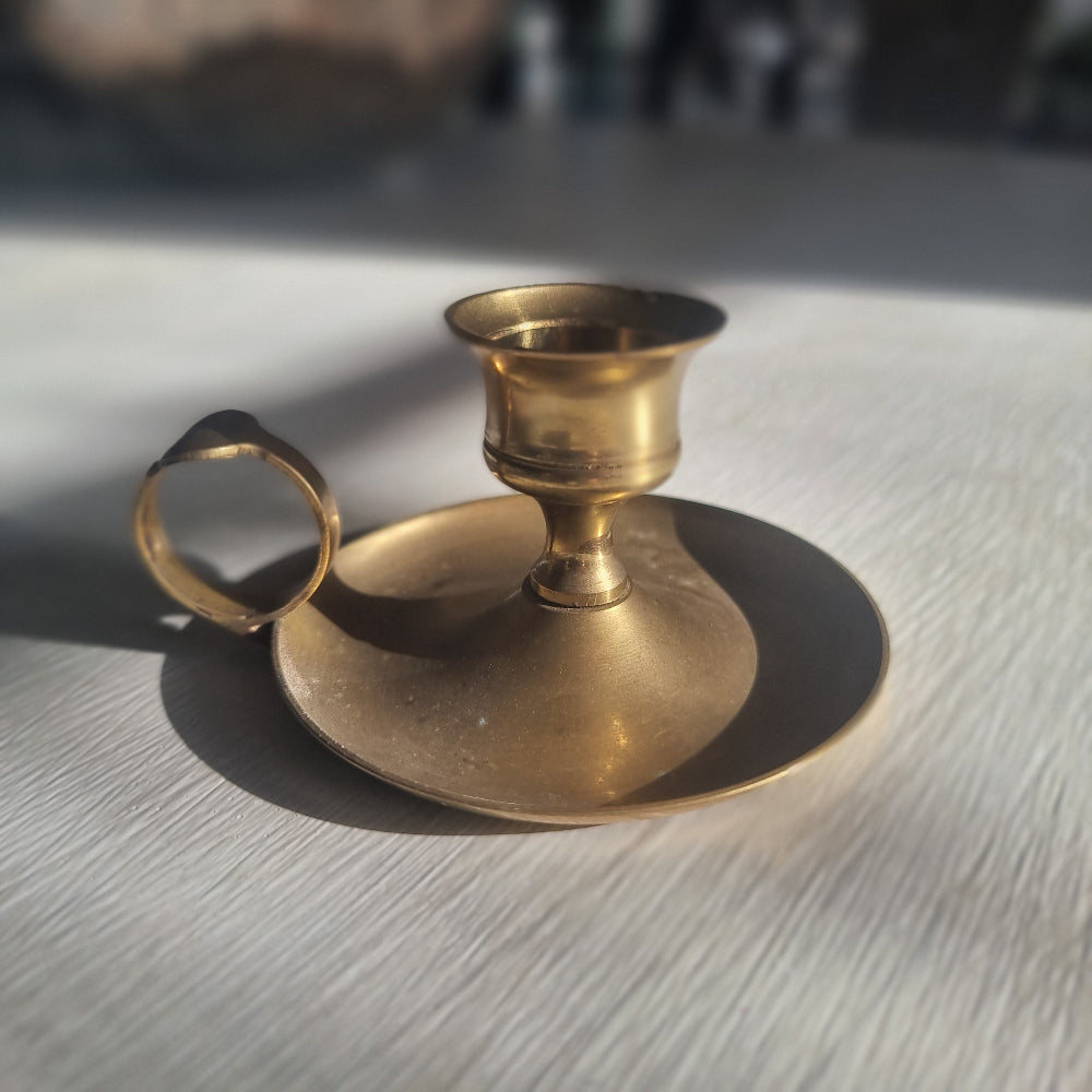 Brass chamber candlestick with round drip tray and finger handle.