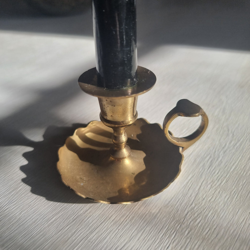 Vintage brass chamberstick with scalloped drip tray and finger handle.