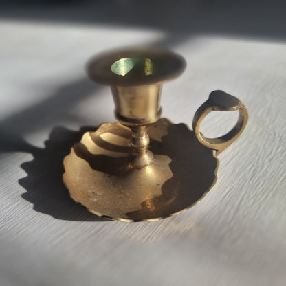 Vintage brass chamberstick with scalloped drip tray and finger handle.