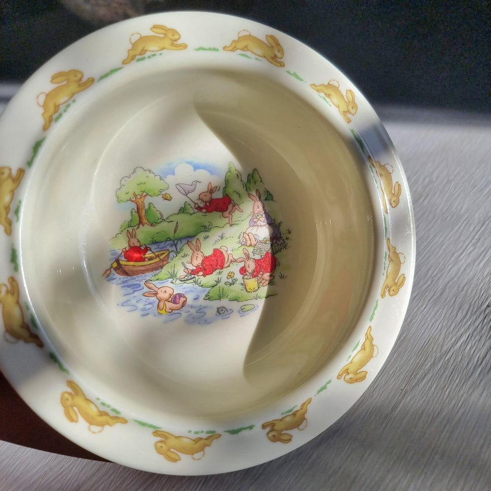 Royal Doulton Bunnykins melamine bowl with rabbit scenes in centre and hopping bunny border around rim.