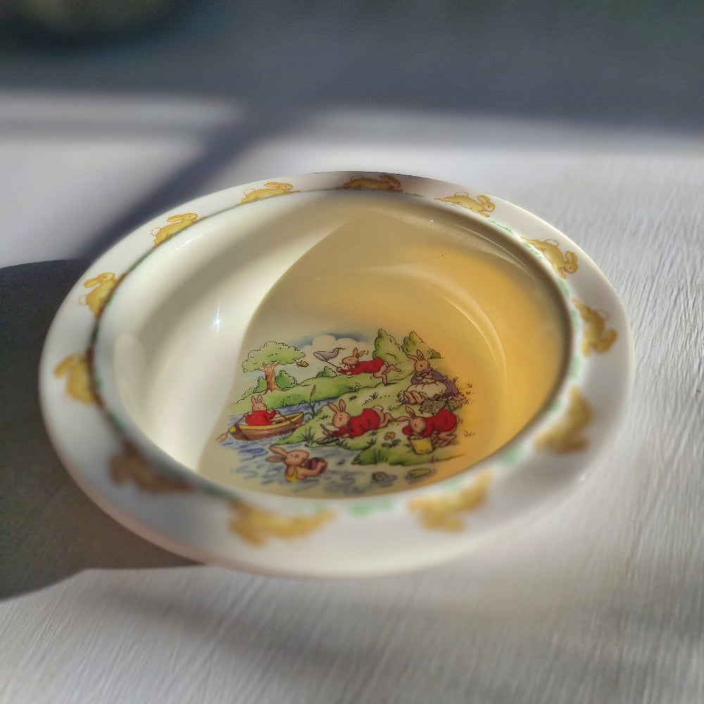 Royal Doulton Bunnykins melamine bowl with rabbit scenes in centre and hopping bunny border around rim.